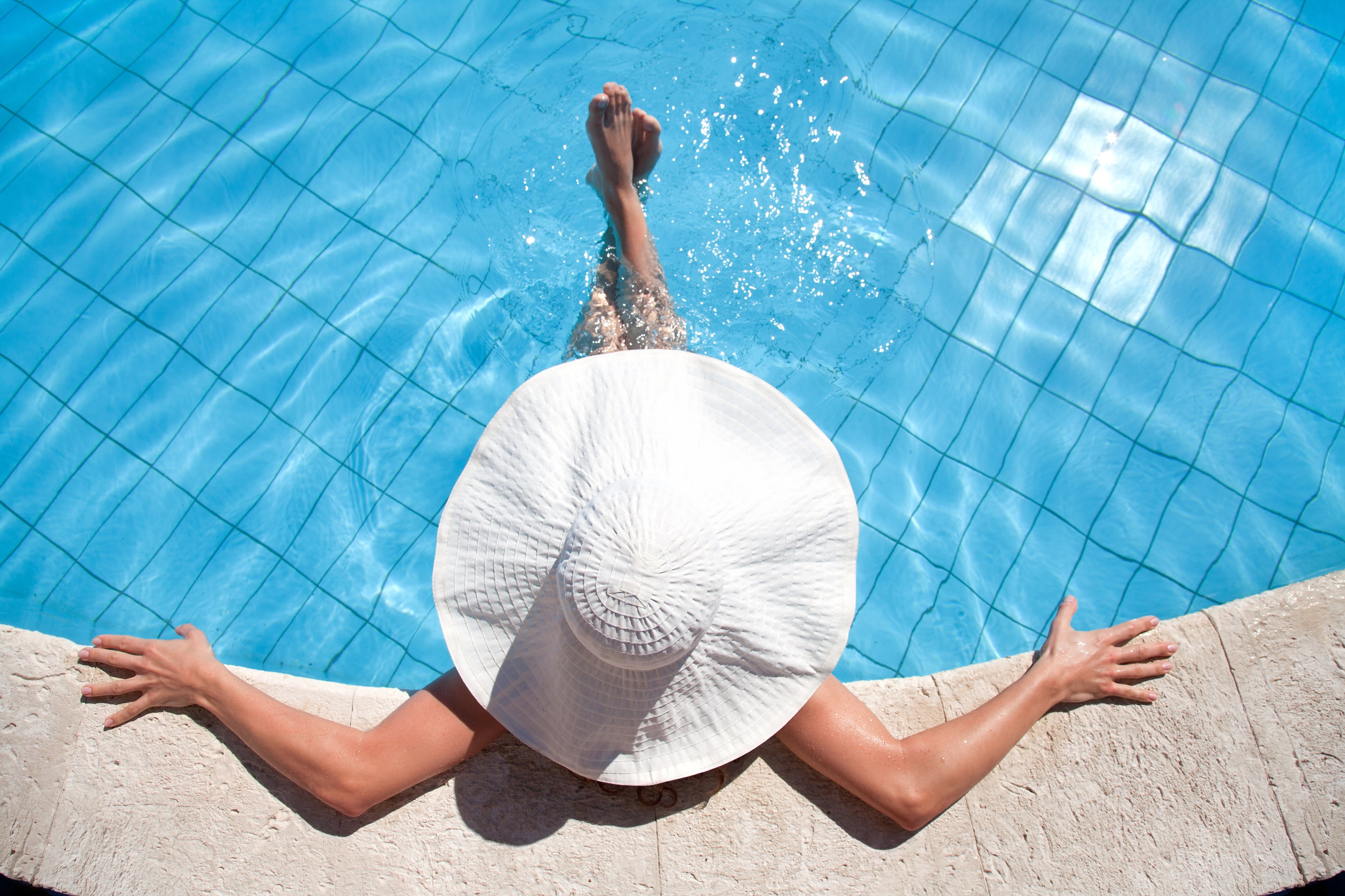 woman in pool with white wide brimmed hat
