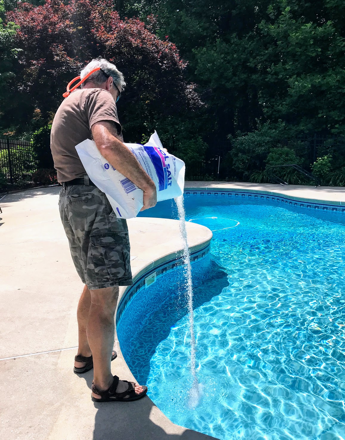 man pouring bag of salt into a pool