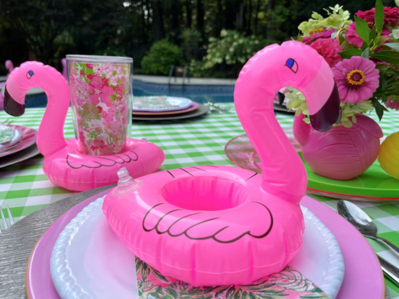 two inflatable pink flamingo coasters on pool party table