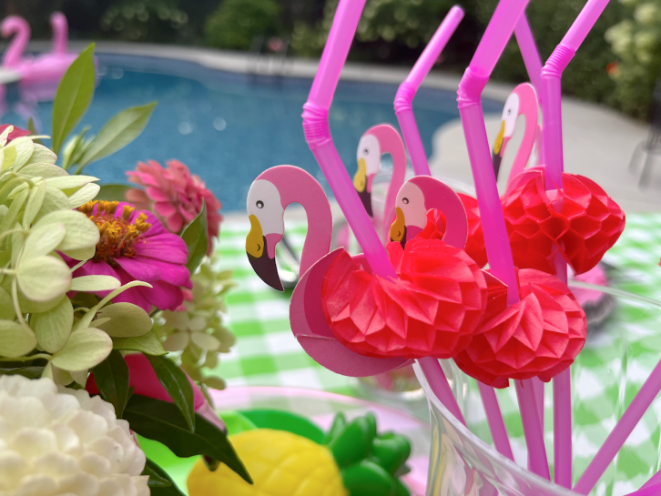 flamingo straws in a cup displayed on a pool party table