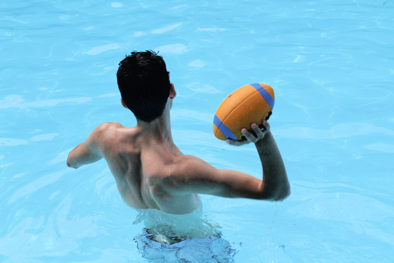 boy throwing football in a swimming pool
