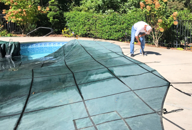 man installing inground pool cover