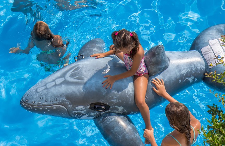 child on a large whale pool float