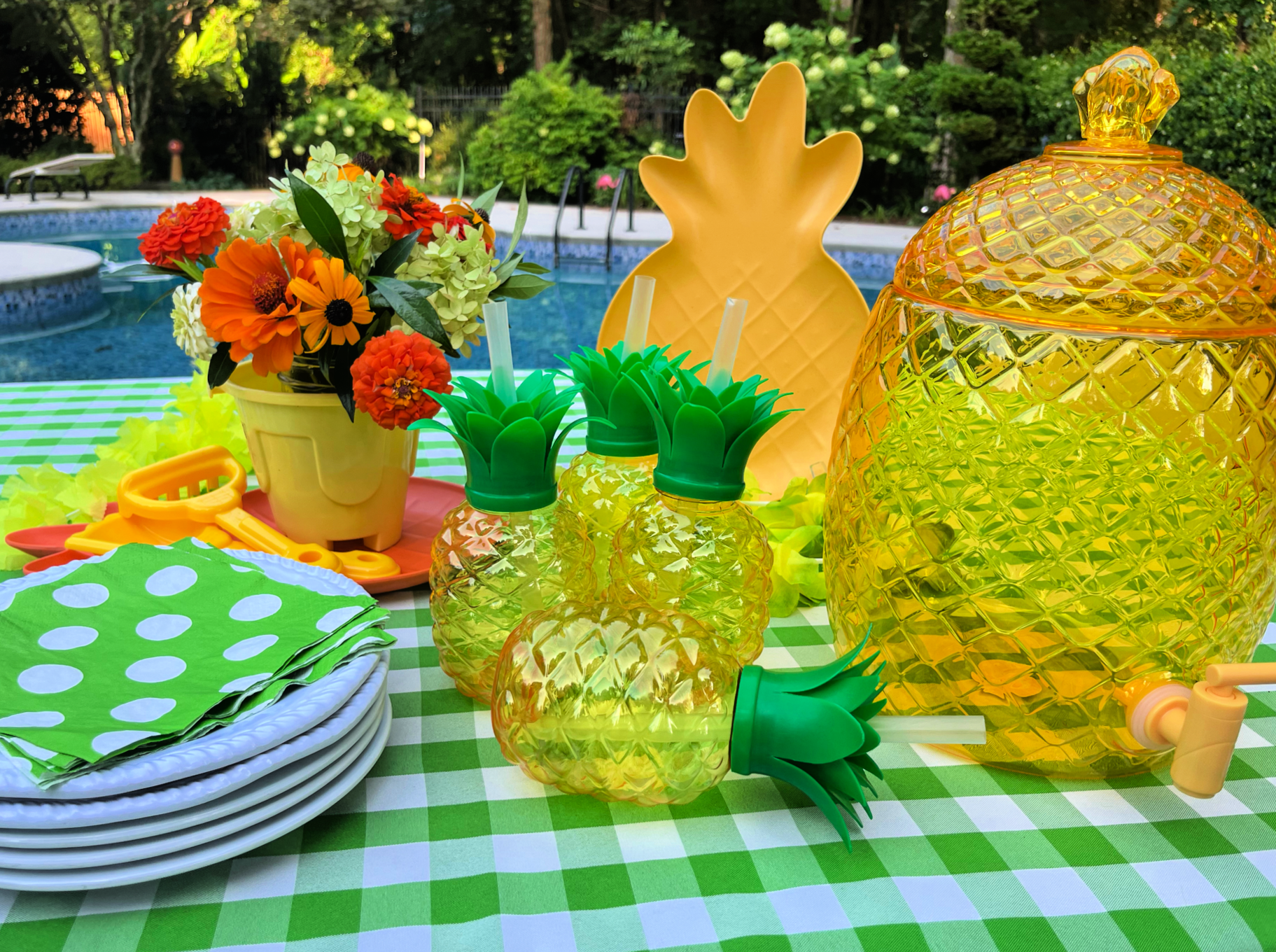 pool party table set with white plates, pineapple shaped cups, and drink dispenser