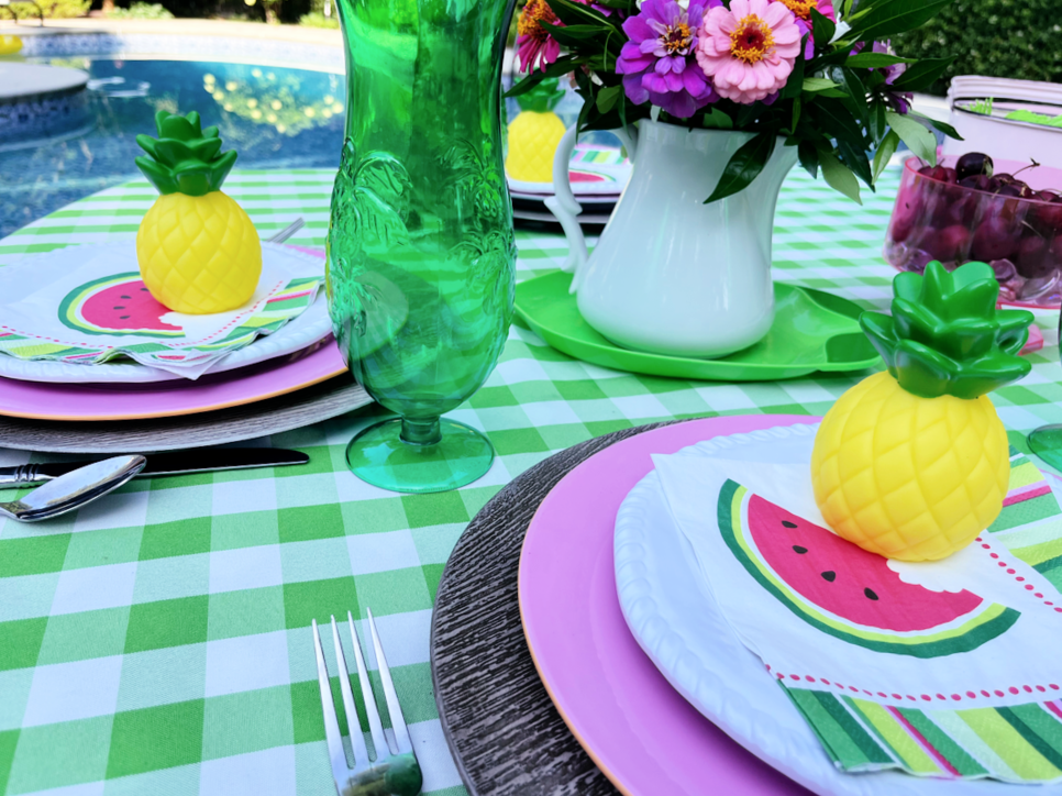 pool party table setting with watermelon napkins, green glasses and pink plates